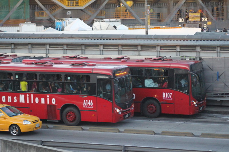 mode of transportation, city, vehicle, transmilenio, street, colombia, bus, land vehicle, motor vehicle, built structure, incidental people, red, motion
