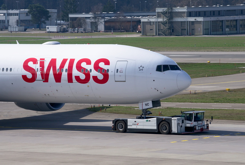 swiss, sign, swiss airlines, boeing 777, built structure, outdoors, road, jet, no people, city, land vehicle, mode of transportation, commercial airplane