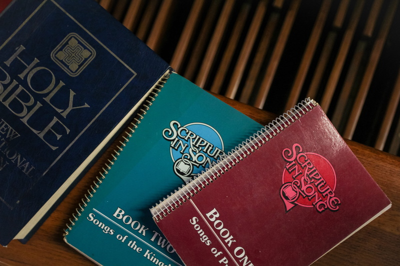 western script, wood - material, books, wooden, gambling, communication, text, book, indoors, publication, blue, spiral, songbook, high angle view, table