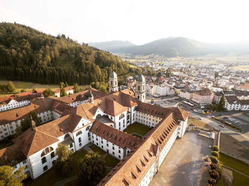 cityscape, built structure, surrounded, town, architecture, sky, roof, residential district, city, daytime, mountain, from above, no people, outdoors, near