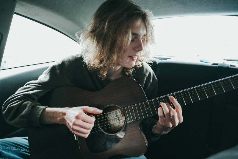 acoustic guitar, young adult, lifestyles, 5K, strum, guitar, musical instrument, women, real people, hair, backseat, front view, vehicle interior, leisure activity