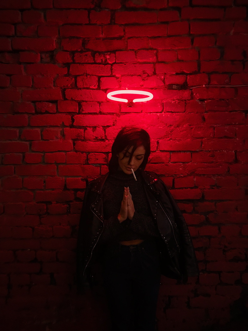 front view, praying, waist up, clothing, lifestyles, neon, night, one person, beautiful woman, casual clothing, wall - building feature, light, real people