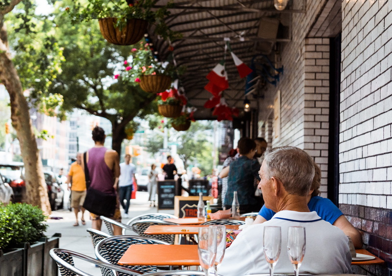 architecture, business, incidental people, outdoors, dining, sitting, crowd, trees, relaxation, outside, city, chair, two, people, cafe, street, glass
