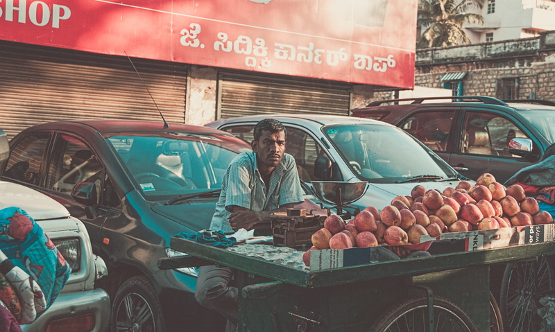 occupation, front, western script, one person, food and drink, man, parked, city, day, sitting, text, land vehicle, fruits, apples, adult, fruit, cart