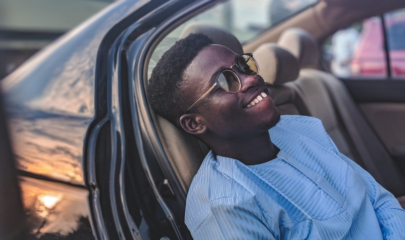 smirk, sitting, only Men, man, adult, one Person, person, young Adult, glasses, mode of Transport, black, inside Of, day, portrait, male Beauty, handsome