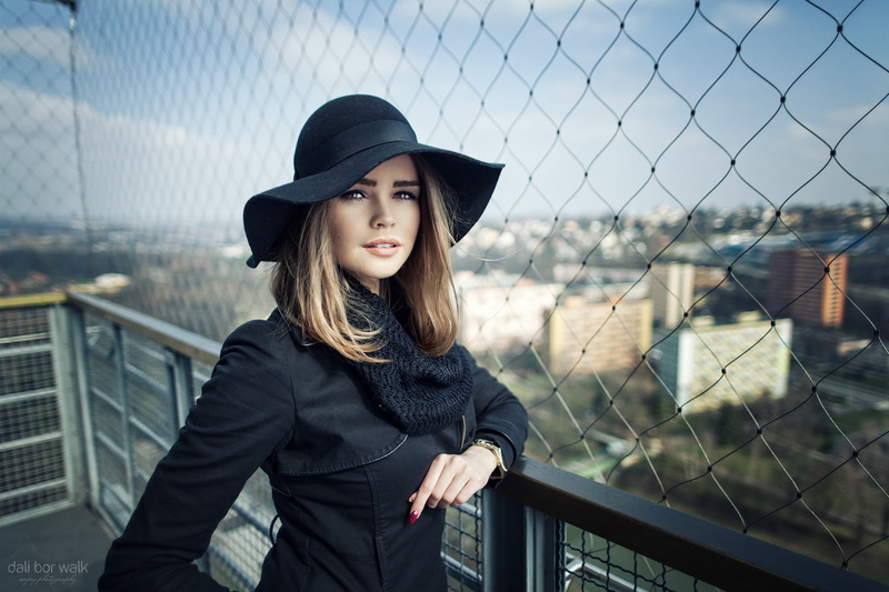 front view, 1080P, depth of field, warm clothing, hat, one person, real people, fence, beautiful woman, face, black clothing, hairstyle, red nails, portrait