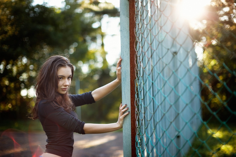 women, real people, tree, chainlink fence, fence, boundary, sunlight, women outdoors, young adult, beautiful woman, barrier, depth of field, leisure activity