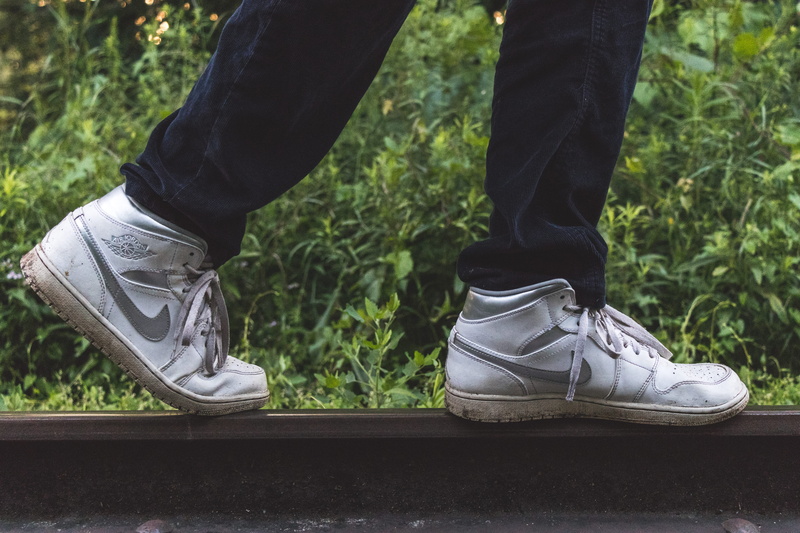 lifestyles, human foot, one person, train tracks, lace - fastener, human body part, outdoors, green, jordan, nature, 5K, focus on foreground, canada, real people