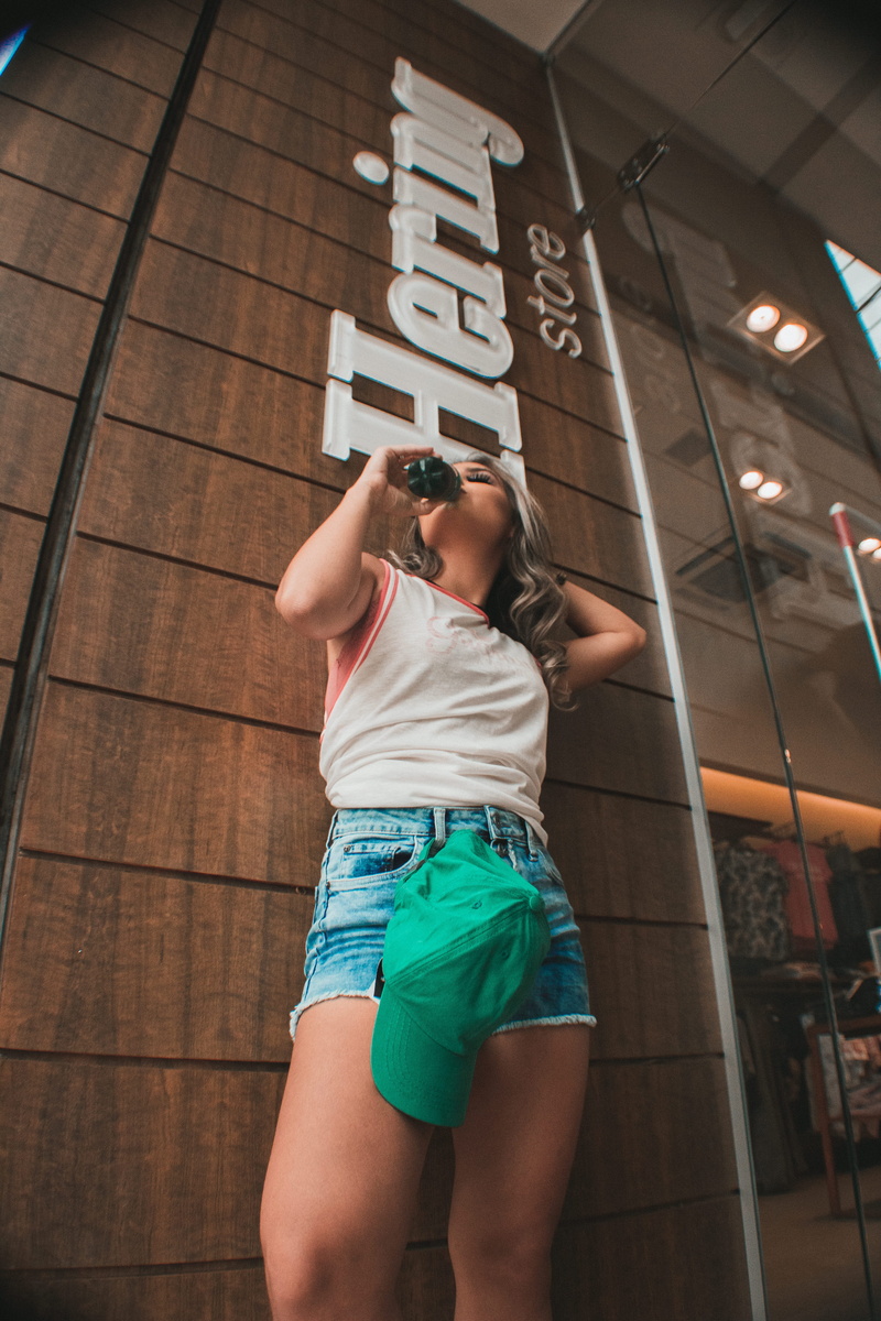 shorts, building, adult, hair, hairstyle, text, flooring, jeans, low angle view, back, wood, human, indoors, women, bottle, sunglasses, lifestyles, accessory