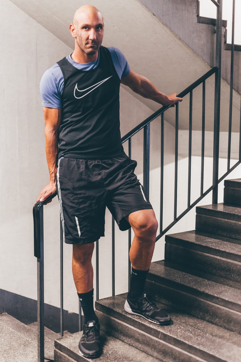 person, wearing, indoors, wall, mature men, railing, leisure activity, real people, man, black, casual clothing, one person, urban, fashion, handrail, metal