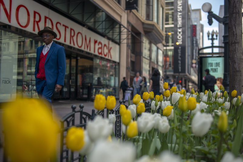 flower, street photography, person, selective focus, western script, built structure, plant, overcoat, apparel, standing, day, town, men, city life, suit