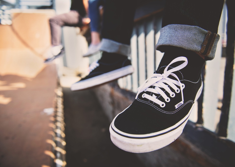 focus on foreground, standing, outdoors, men, person, rail, human leg, lifestyles, sunlight, sneakers, wearing, real people, hand, black, leisure activity