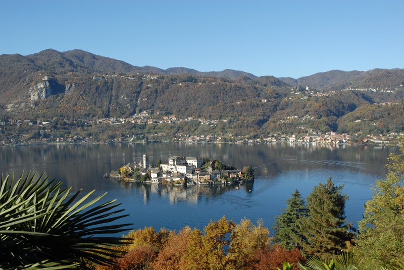 beauty in nature, clear sky, day, water, orta san giulio, lake orta, reflection, tranquility, tree, environment, plant, nature, tranquil scene, sky, outdoors