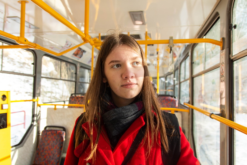 front view, banister, looking at camera, seat, young women, hair, one person, tram, young adult, overcoat, handrail, passengers, hairstyle, czechia, public transport