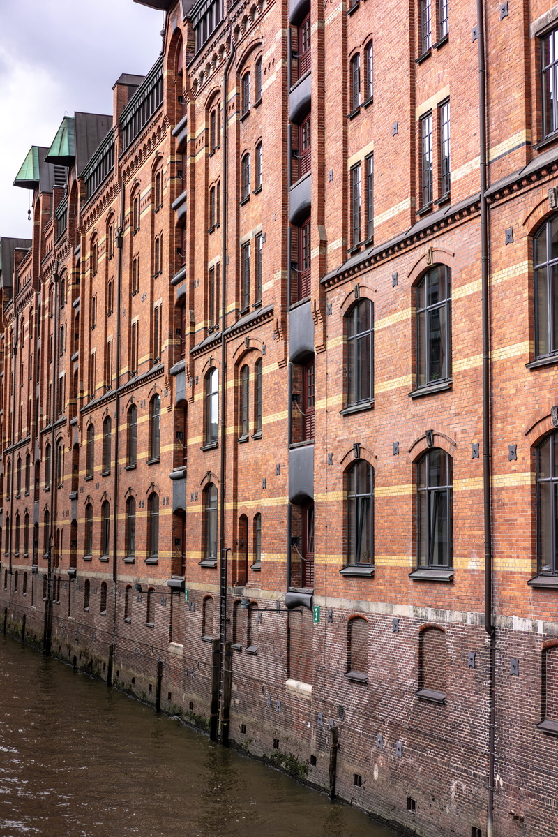 vehicle, sky, window, cloud - sky, built structure, water, in a row, city, canal, brick, outdoors, speicherstadt, travel, building exterior, urban, residential district