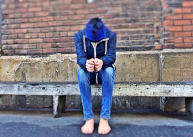 teenager, daytime, jeans, emotion, outdoors, photography, hood, blue jeans, brick, sitting, youth, focus, homeless, sadness, one person, bench, brick wall