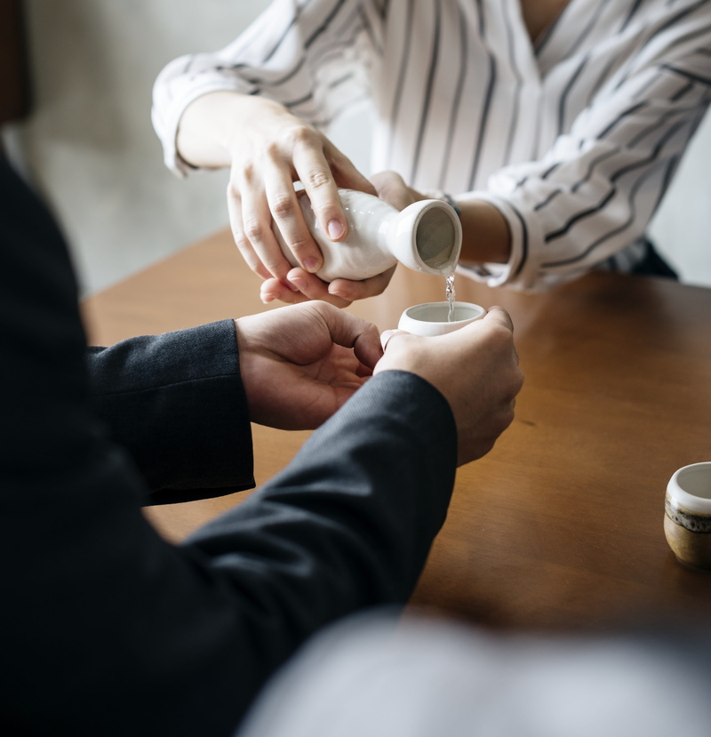 human hand, tavern, indoors, pouring, sitting, drink, alcohol, two people, midsection, selective focus, japanese, sake, cup, asian, people, socialize, human body part
