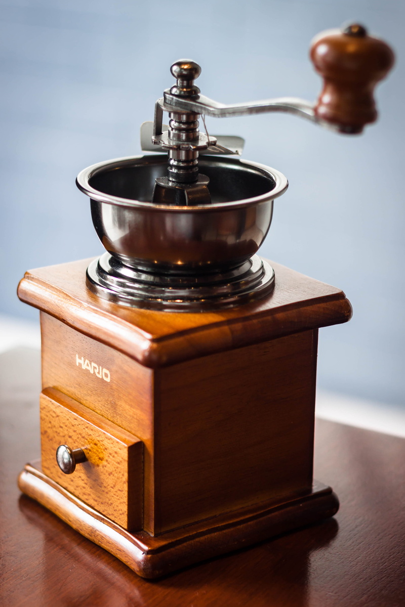 indoors, coffee - drink, container, natural light photography, nature, focus on foreground, coffee grinder, table, wood - material, human body part, 4K