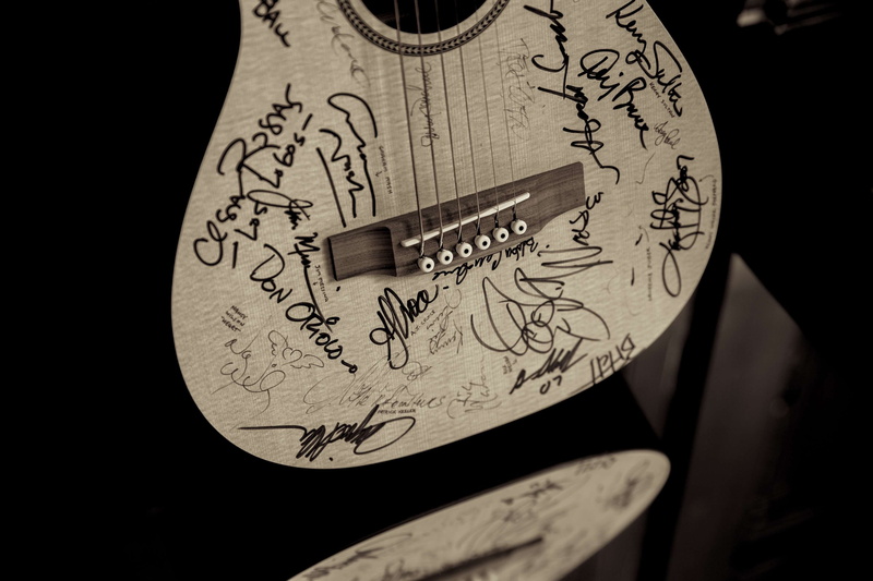 indoors, no people, architecture, communication, wood, acoustic guitar, focus on foreground, representation, studio shot, single object, black background