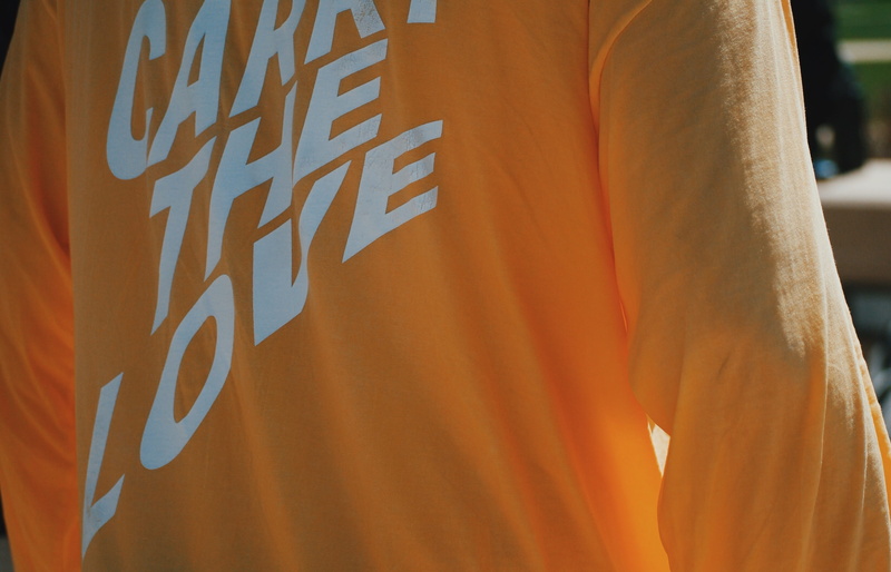 sunlight, human body part, stain, orange color, day, carry the love, standing, one person, rear view, applique, text, calligraphy, indoors, home decor