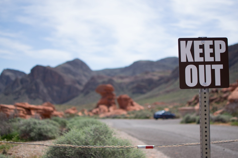 focus on foreground, road sign, rock, road trip, usa, sky, national park, keep out, nevada, shield, text, day, road, landscape, environment, mountain, guidance