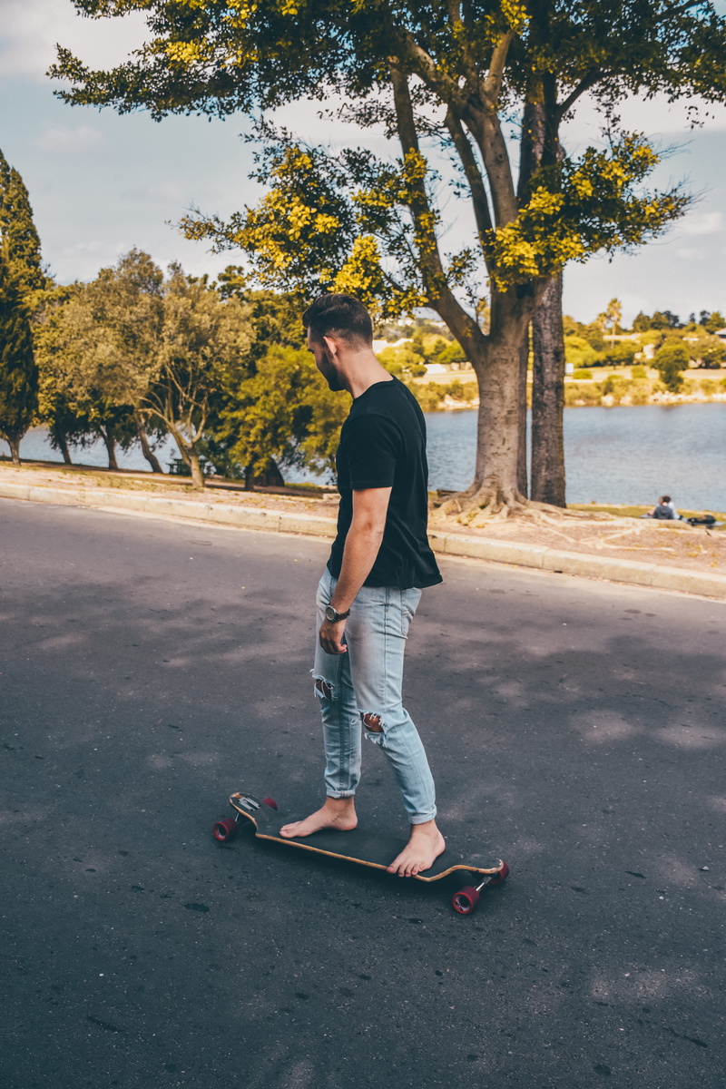 side view, tarmac, handrail, lifestyles, clothing, standing, young men, jeans, sport, person, young adult, pants, man, sleeve, plant, daytime, balance