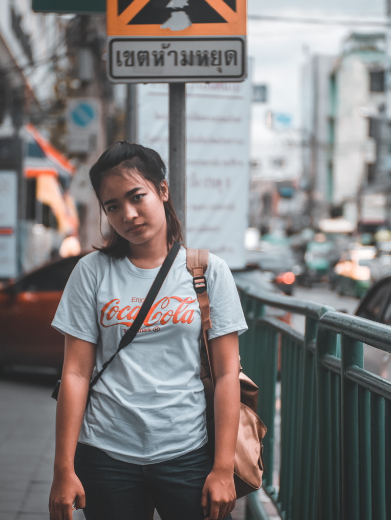 mode of transportation, looking at camera, shirt, vehicles, near, one person, young adult, woman, blur, wear, city, focus, urban, lady, real people, wearing
