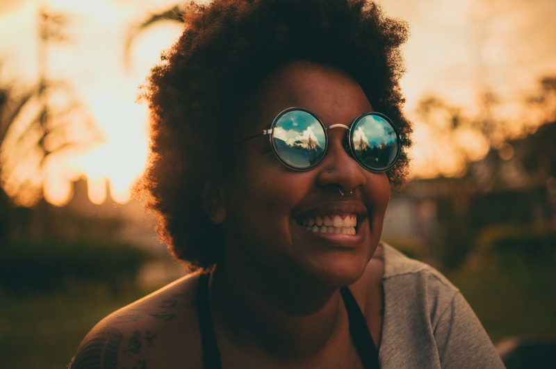 glasses, wearing, happy, outdoors, girl, eyewear, woman, sky, curly hair, emotion, fun, focus on foreground, sunglasses, face, close-up, lens flare, fashion