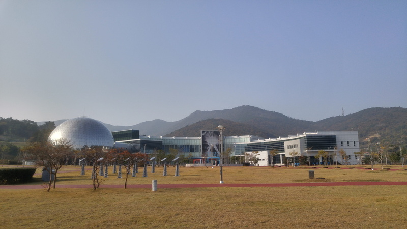Jeollanam-Do, outdoors, mountain, sky, built structure, playing field, Boo, field, grass, goal post, soccer, clear sky, nature, group of people, building exterior
