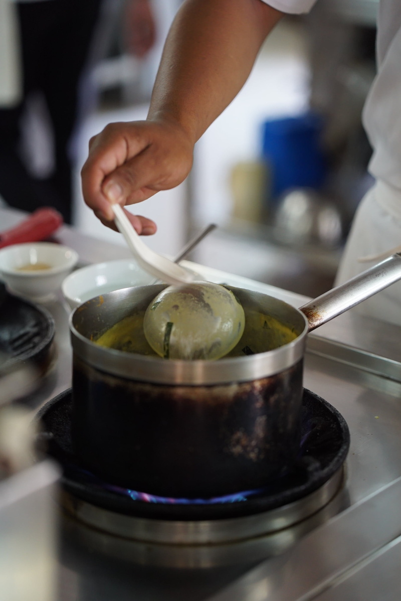 selective focus, holding, hand, chefs, spoon, sear, pan, domestic room, food, knob, kitchen utensils, real people, cooking, kitchen, human body part, close-up