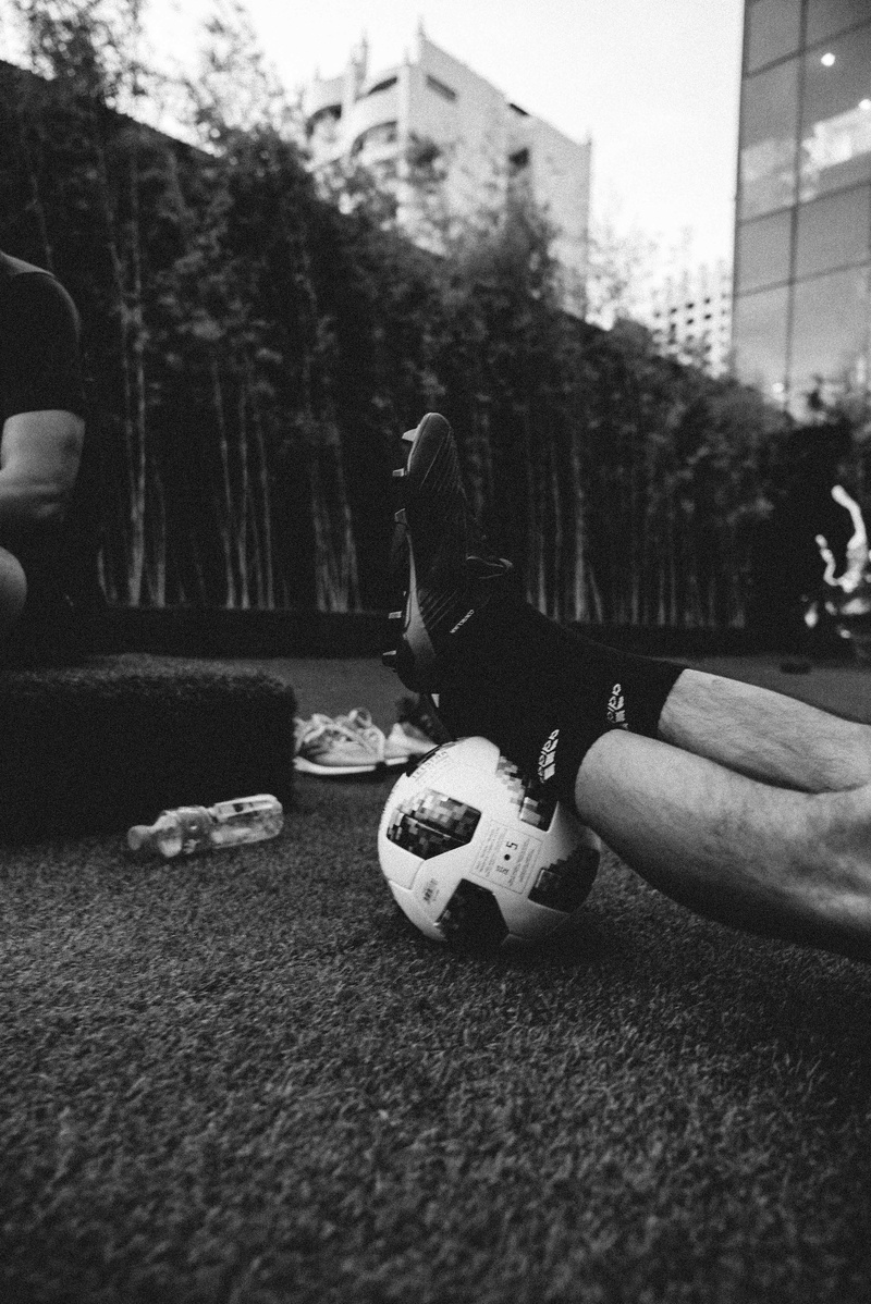 outdoors, hand, toy, scale, building exterior, feet, selective focus, soccer, gray, architecture, city, ball, body part, real people, boots, leisure activity