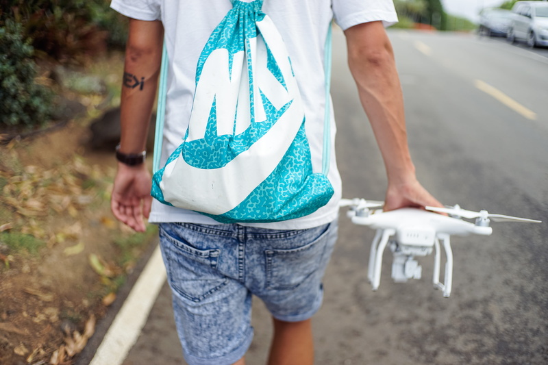c, holding, men, white, carrying, leisure activity, guy, tech, walking, sport bag, standing, outdoors, road, front view, day, roadway, technology, quadcopter