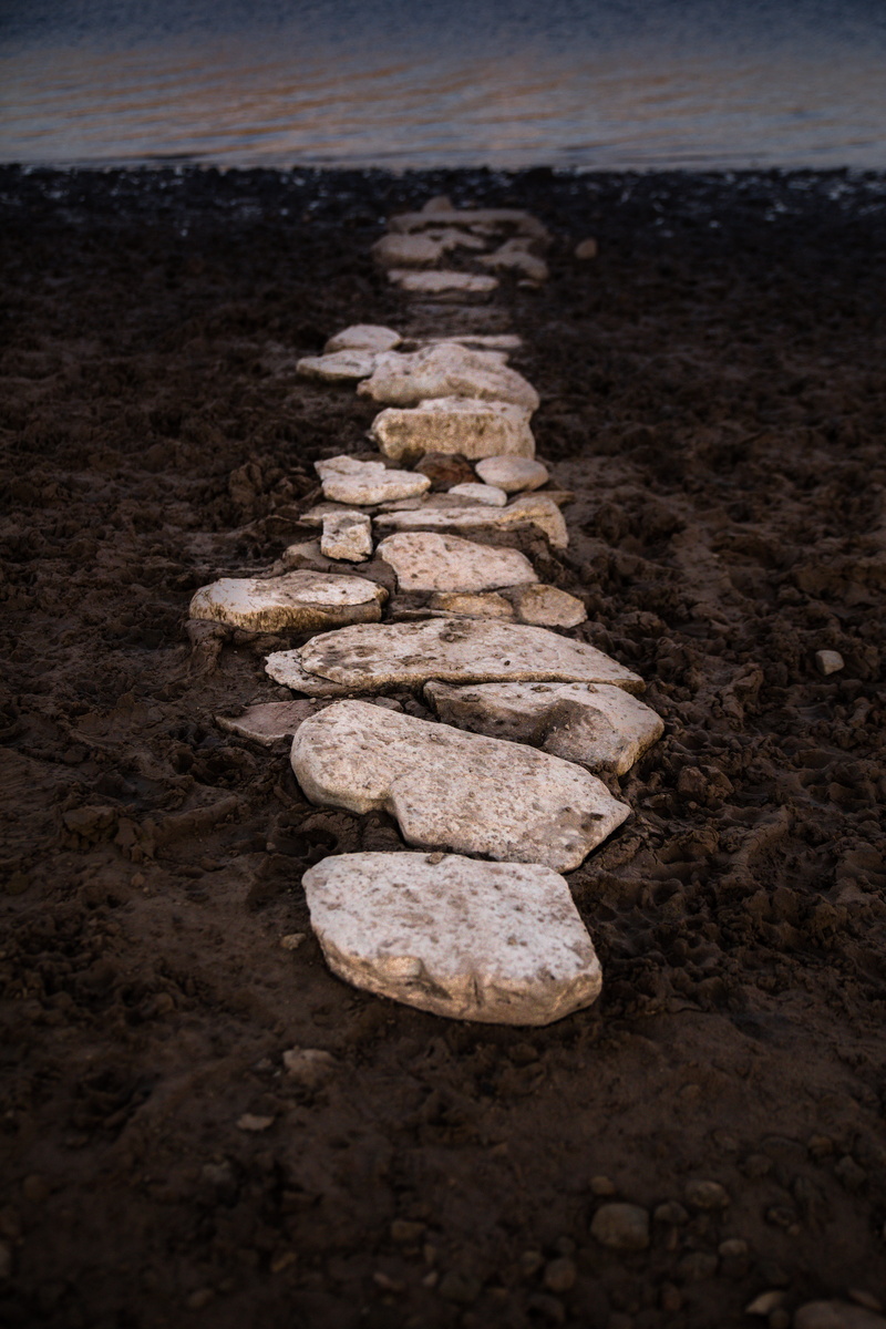 wilderness, beauty in nature, stone - object, sidewalk, beach, walkway, stones, high angle view, dirt road, shore, road, balance, sky, day, outdoors, pebble