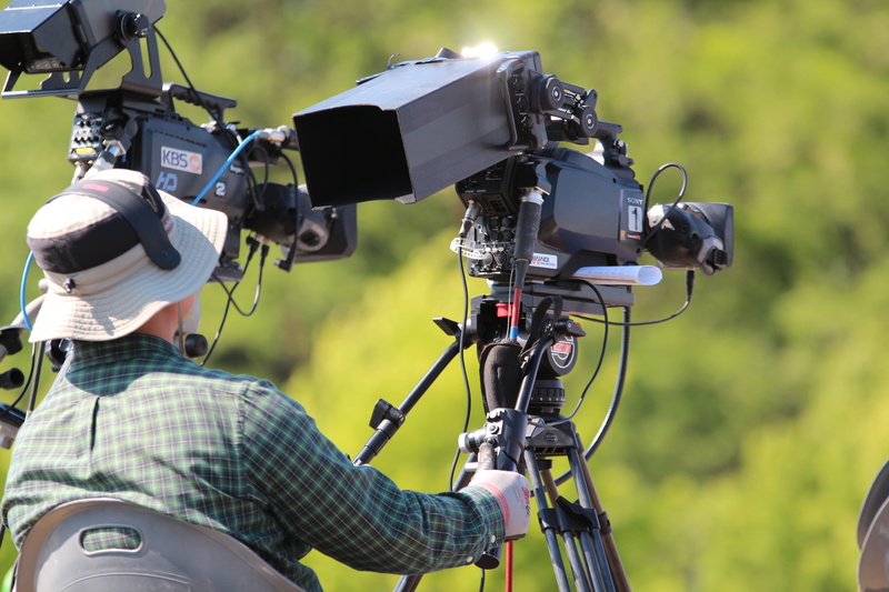 television camera, people, filming, event, daytime, motion, dress, focus on foreground, day, outdoors, activity, camera, broadcasting, videocam, person