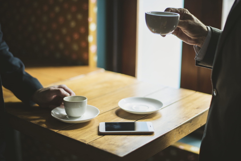 one person, refreshment, drinking, food and drink, drink, wood, wooden table, human body part, holding, saucer, hand, human hand, formal, cup, indoors
