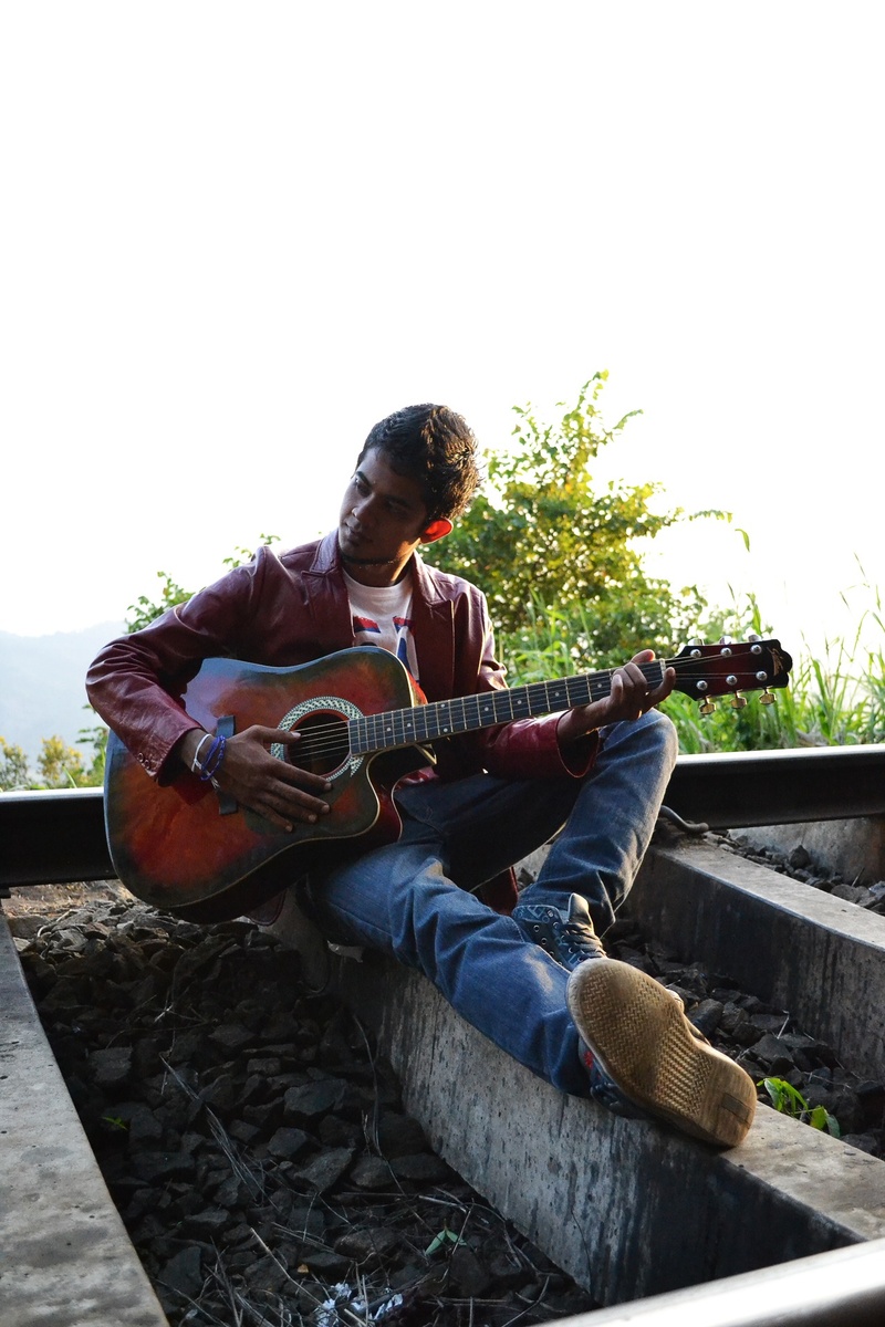 artist, playing, scene, path, leisure activity, mawanella, musical instrument, sitting, rail road, rails, guitar, one person, plucking an instrument, music