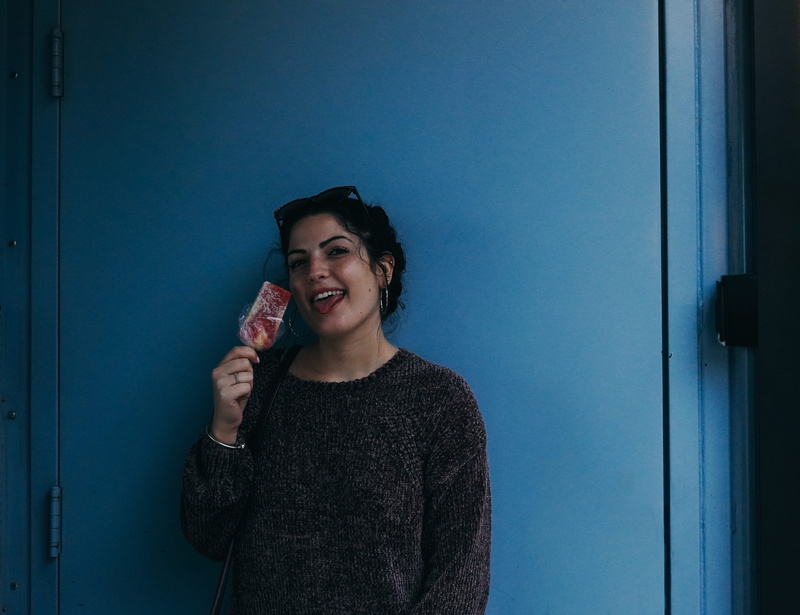 front view, beautiful woman, young adult, tongue, ice pop, emotion, teeth, door, smiling, leisure activity, woman, sweater, long sleeve, holding, human