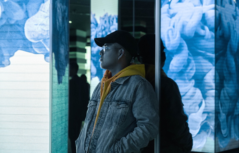 standing, banister, coat, word, jacket, real people, glass - material, hat, young adult, handrail, looking, profile view, door, tire, clothing, store, window