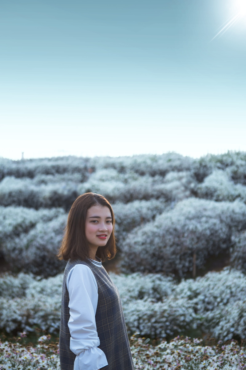 hair, top, plant, apparel, looking at camera, standing, leisure activity, young adult, one person, non-urban scene, grey, sky, nature, casual clothing