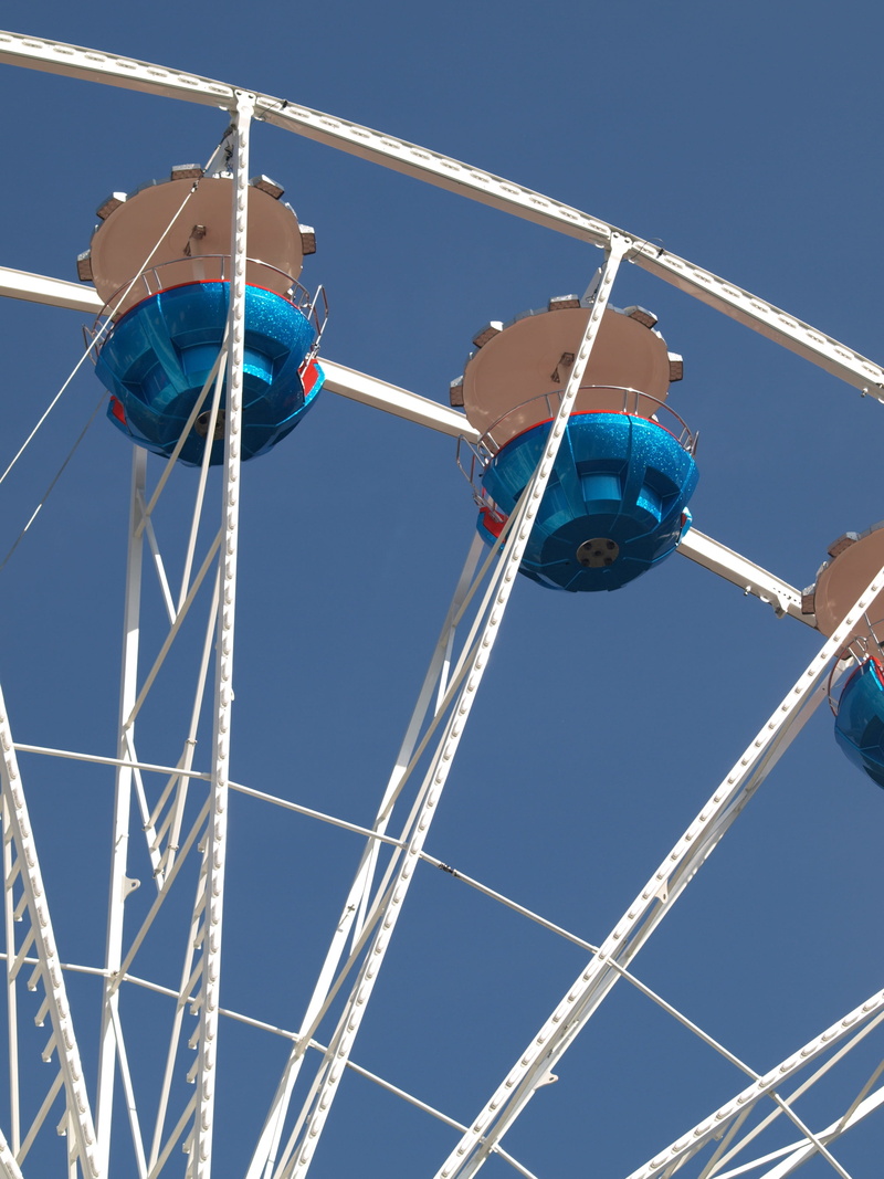 low angle view, architecture, fun, festival site, year market, blue, clear sky, outdoors, wheel, fairground, excitement, arts culture and entertainment