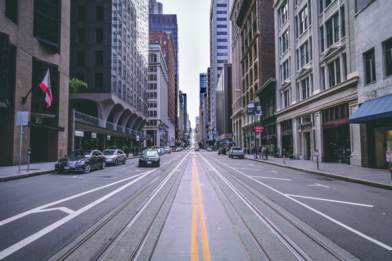 city street, land vehicle, office building exterior, way, vehicles, marking, diminishing perspective, high, flag, buildings, town, architecture, symbol