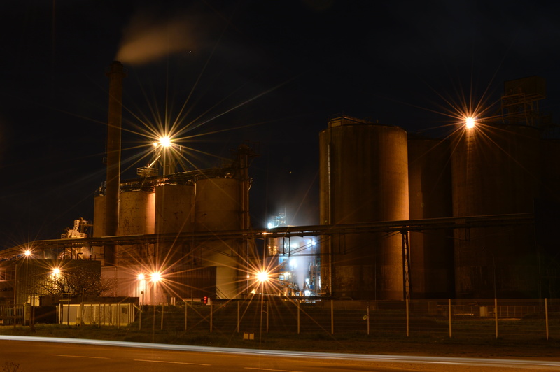 outdoors, night, street light, business, steel, factory, lens flare, lighting equipment, 5K, building exterior, illuminated, oil industry, industry, high