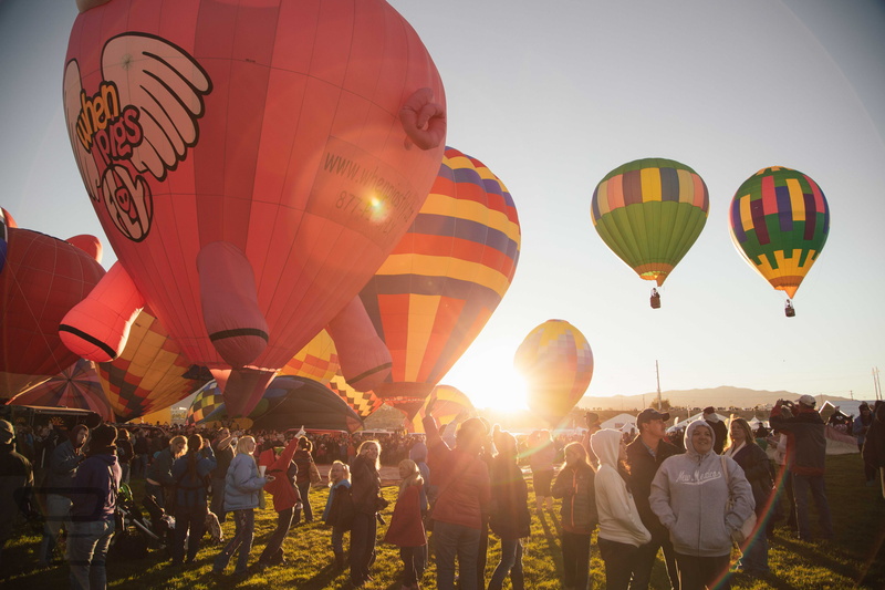 standing, color, sunbeam, flying, hot air balloon, air, near, large group of people, ballon fiestum, sky, balloon, lens flare, assorted, celebration, sunshine
