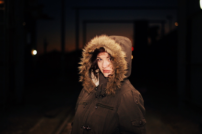 focus on foreground, portrait, headshot, brown hair, contemplation, front view, outdoors, canada, long hair, night, 2K, mid adult, hood - clothing, clothing