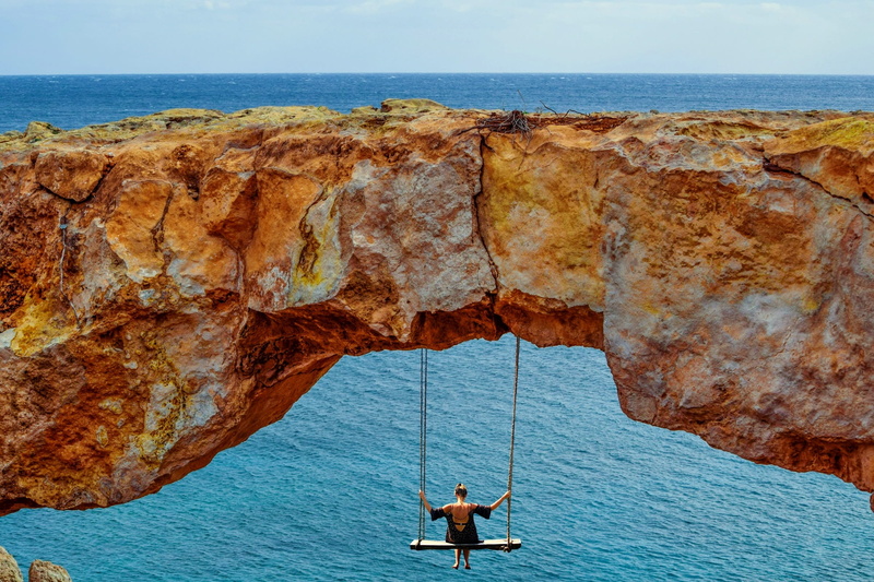 stone coast, one person, woman, tranquil scene, rock, swinging, cliff, scenics - nature, steinig, rock arch, horizon, beauty in nature, rocky coast, lifestyles