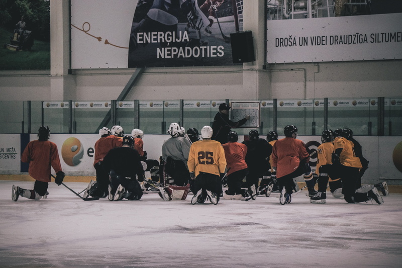 built structure, real people, text, field, hockey, city, coach, 5K, sign, building exterior, group of people, non-western script, ice hockey, front, player