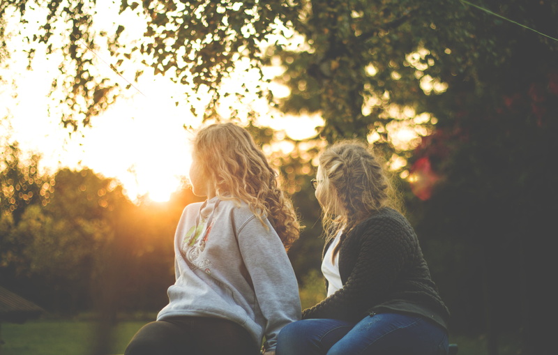 fall, real people, kids, women, looking back, people, two people, girls, near, children, backlit, green, happy, hair, sitting, adult, park, sisters, wear