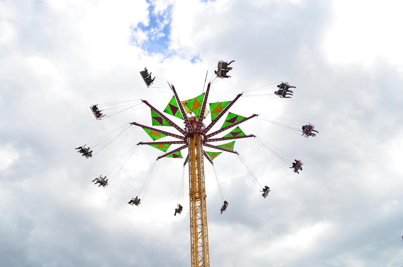 arts culture and entertainment, spinning, chain swing ride, carnival, excitement, day, sky, low angle view, high up, group of people, amusement park, fun
