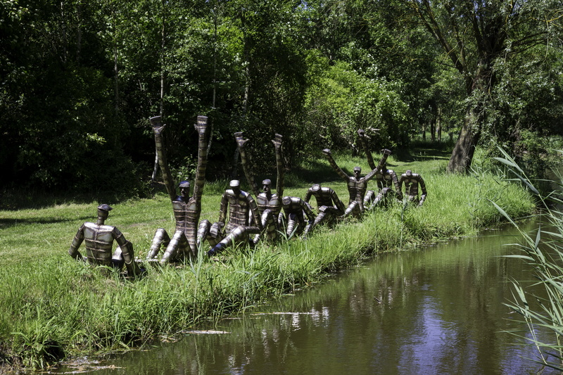 the rowers, plant, day, group of animals, steel group sculpture, lake, animal themes, real people, water-side, nature, water, waterfront, green color, sunshine