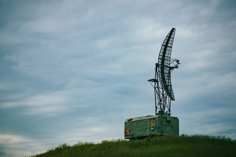 low angle view, grass, military, land, machinery, no people, sky, industry, satellite dish, connection, radio wave, day, plant, radio, hill, clouds, radar